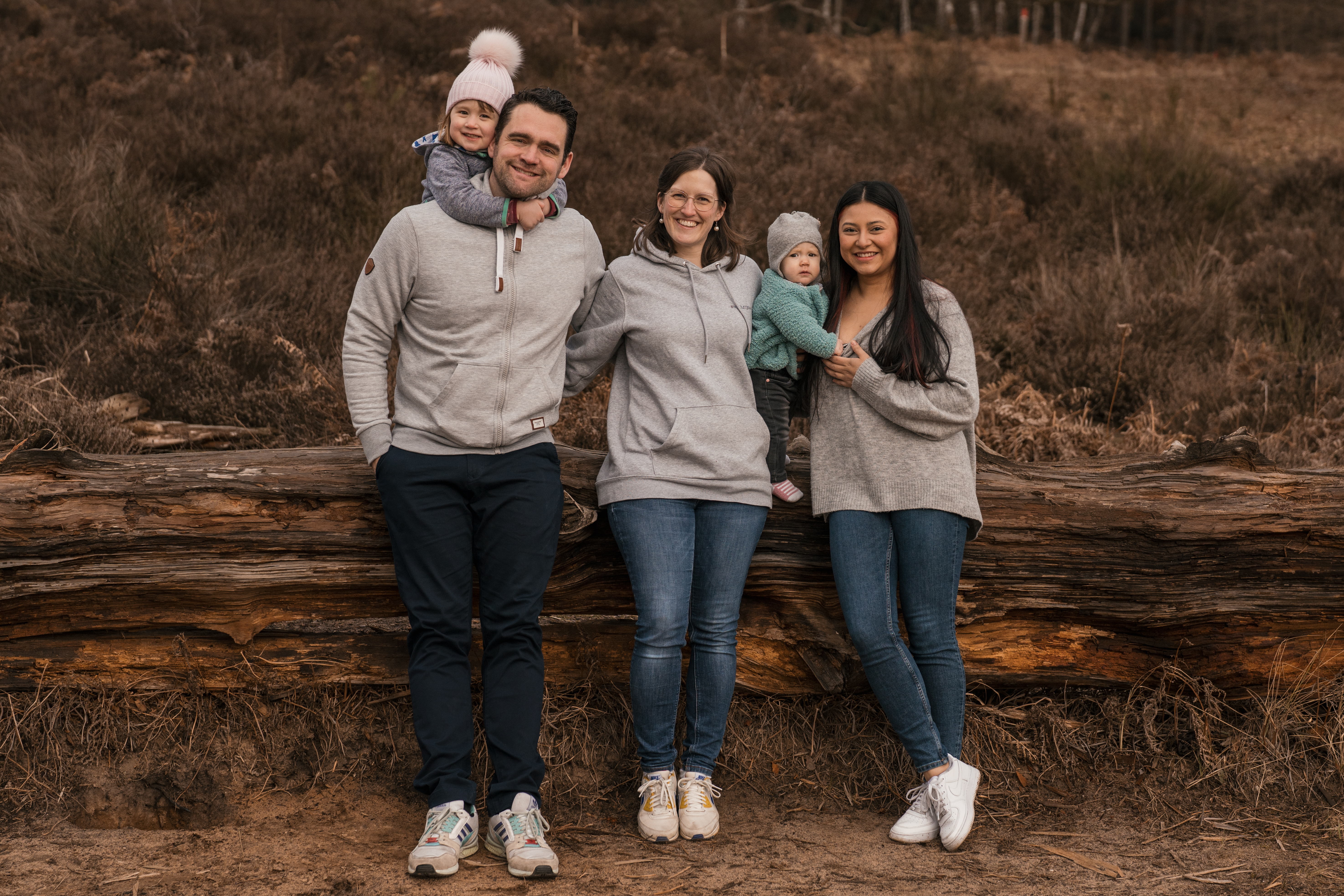 Foto einer 5-köpfigen Familie in der Natur. Die 2 jüngsten Kinder sind in den Armen der Eltern. - Familienshooting Outfit Tipps
